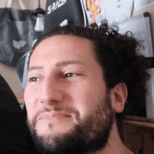 a man with a beard is smiling in front of a s racer chair
