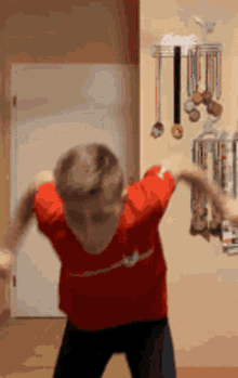 a boy in a red shirt is dancing in front of a wall with medals on it