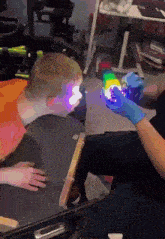 a person in a blue glove is holding a rainbow colored cube in front of a child in a wheelchair