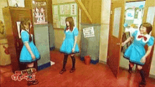 three girls in blue dresses are dancing in a hallway .