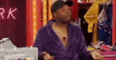 a man in a purple robe and hat is standing in a room .