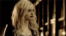 a woman with long blonde hair is standing in a dark room .