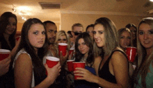 a group of people are holding red cups and one woman is making a funny face
