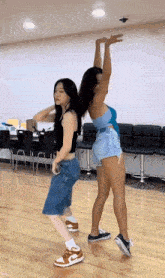 two women are dancing in a room with their arms in the air .