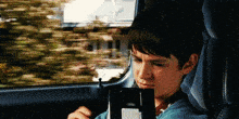 a young boy is sitting in a car looking at a vhs tape