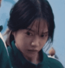 a close up of a woman 's face with a green jacket on .