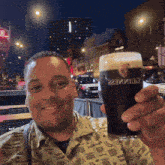 a man is holding a glass of guinness in his hand