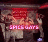 a group of people are dancing on a stage in front of a sign that says " spice gays " .