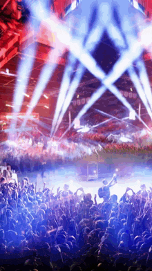 a crowd of people at a concert with blue and red lights coming from the stage