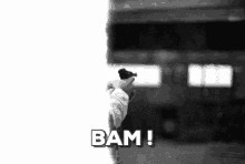 a black and white photo of a person holding a gun in front of a train and the words bam !