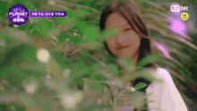 a girl is smiling while standing in a forest .