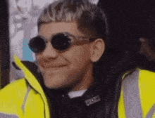 a close up of a man wearing sunglasses and a yellow jacket .