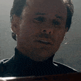 a close up of a man 's face with a turtleneck