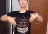 a young man is wearing a black shirt with a skull on it .