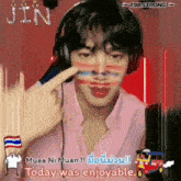 a man wearing headphones and a pink shirt has a finger on his nose