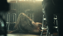 a woman is laying on the floor in a room with stools