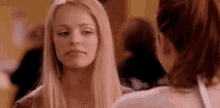 a woman with blonde hair is looking at another woman in a room .