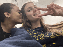 a girl wearing a sweatshirt that says t2 on it kisses another girl on the cheek