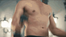 a shirtless man is standing in a room with his hands outstretched .