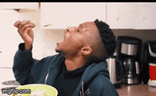 a man is eating food from a bowl with a spoon in his mouth