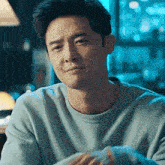 a man in a blue sweater is sitting at a table in a restaurant .