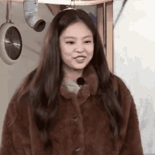 a woman wearing a brown fur coat is smiling and looking at the camera