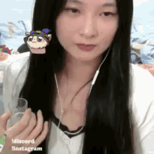 a woman with long black hair is wearing earphones and holding a glass of water .