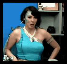 a woman with blue paint on her face is wearing a blue tank top and a white necklace