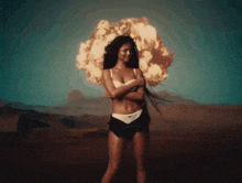 a woman standing in front of an explosion in the desert