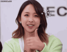a woman giving a thumbs up in front of a sign that says ec