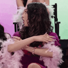 a woman with curly hair is wearing a pink feather boa