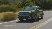 a green volkswagen is driving down a road with motorweek.org written on the bottom