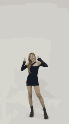 a woman in a black dress is laughing and covering her mouth with her hand .