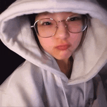 a woman wearing glasses and a white hoodie with the letter a on the front