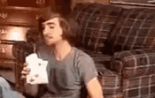 a man is sitting on a couch holding a cup of milkshake .