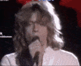 a close up of a man singing into a microphone .