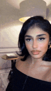 a woman in a black off the shoulder top is looking at the camera