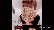 a person is holding a fan of money in front of their face .