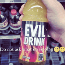 someone is holding a bottle of evil drink in their hand