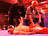 a referee in a striped shirt is standing next to a wrestler laying on the ground