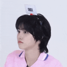 a young man wearing a pink shirt has a sign on his head that says oioi