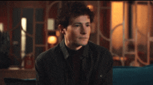 a man with curly hair is sitting on a blue couch in front of a screen that says " avancedna "