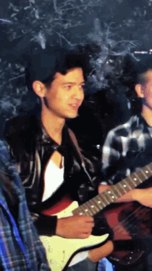 a man playing a guitar with a black hat on