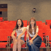 a girl wearing a promise shirt sits next to a girl wearing a 99 shirt