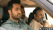 three men are sitting in a car with the letters kvvcsr on the bottom