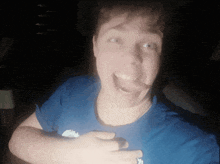 a man in a blue shirt is making a funny face with his mouth open