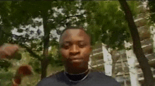 a man in a black shirt is making a funny face with his hands .