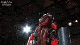 a woman in a red mask is standing in a ring with a sword .