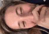 a close up of a woman laying on her back with her eyes closed and her hand on her face .