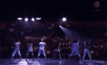 a group of people are dancing on a stage in front of a crowd ..